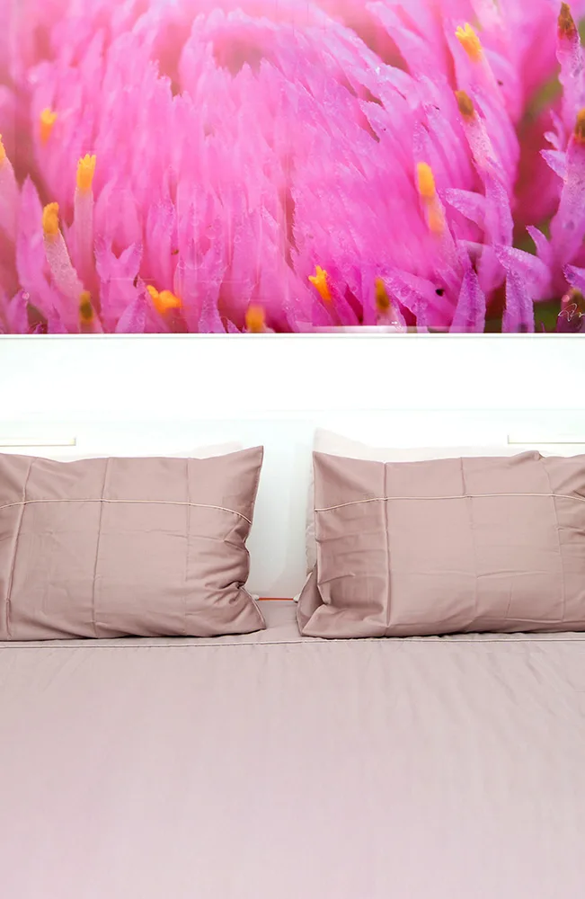 Representative hotel space: A bed with pale pink bedding sits beneath a bright floral wall image.