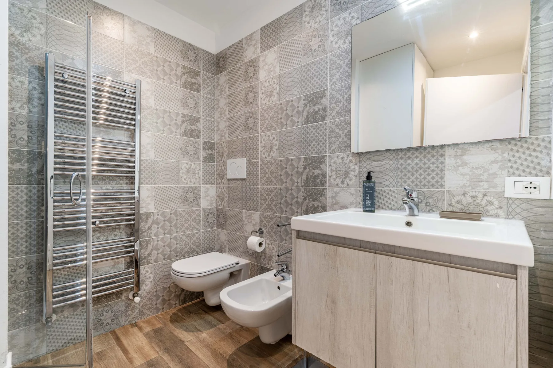 Un baño alicatado con un inodoro suspendido y un amplio mueble con lavabo.