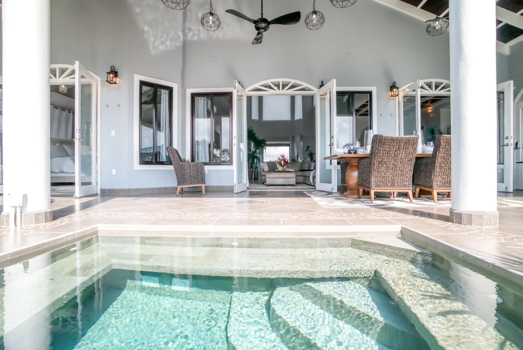 A shallow indoor pool sits in front of an open living area with seating.