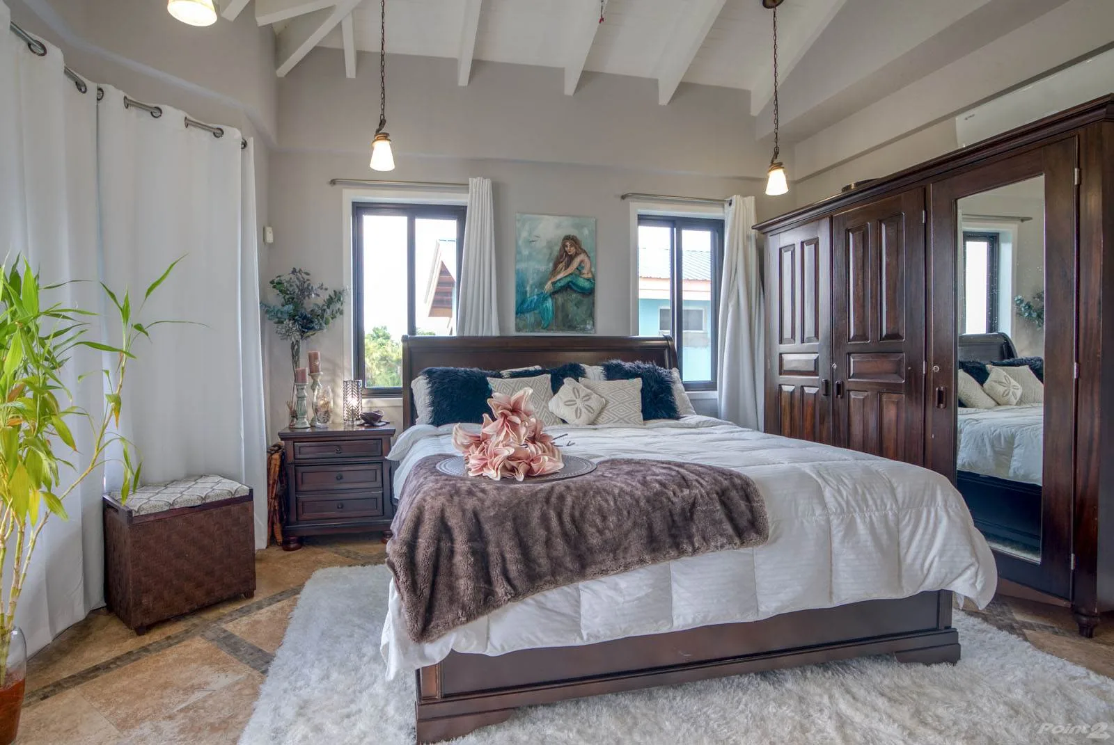 A bedroom with a large bed, dark wood furnishings, and windows.