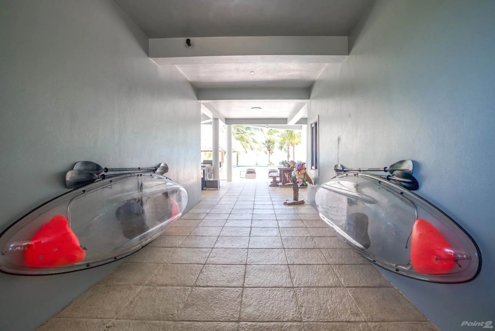 A tiled passage opens onto a bright outdoor seating area, with clear display cases along the walls.