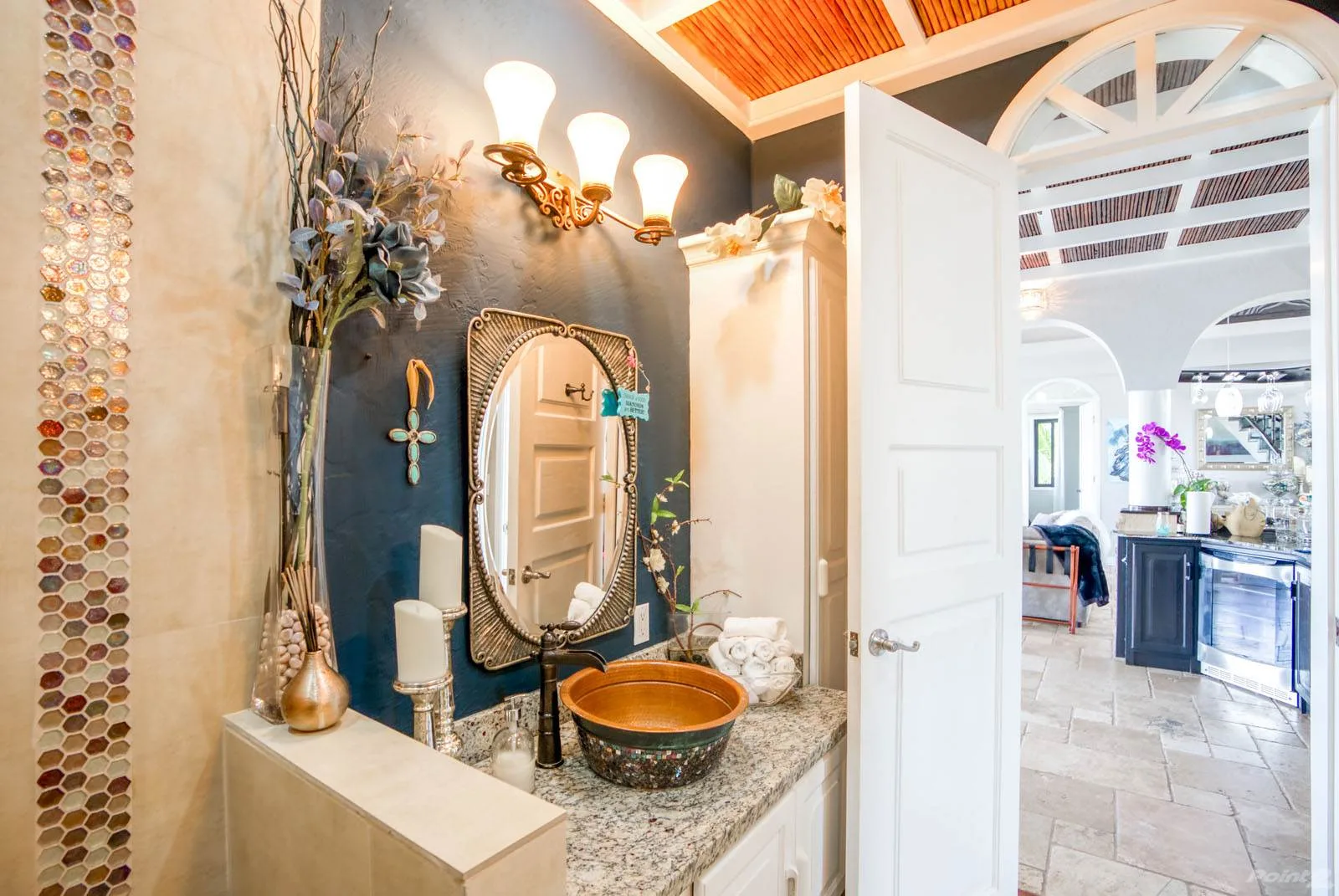A decorative vanity area opens through a white door into a bright adjoining room.