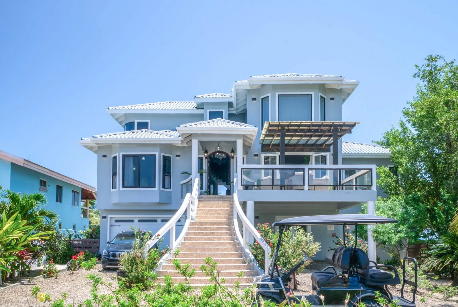 A large multi-level house with a central staircase and covered outdoor seating.