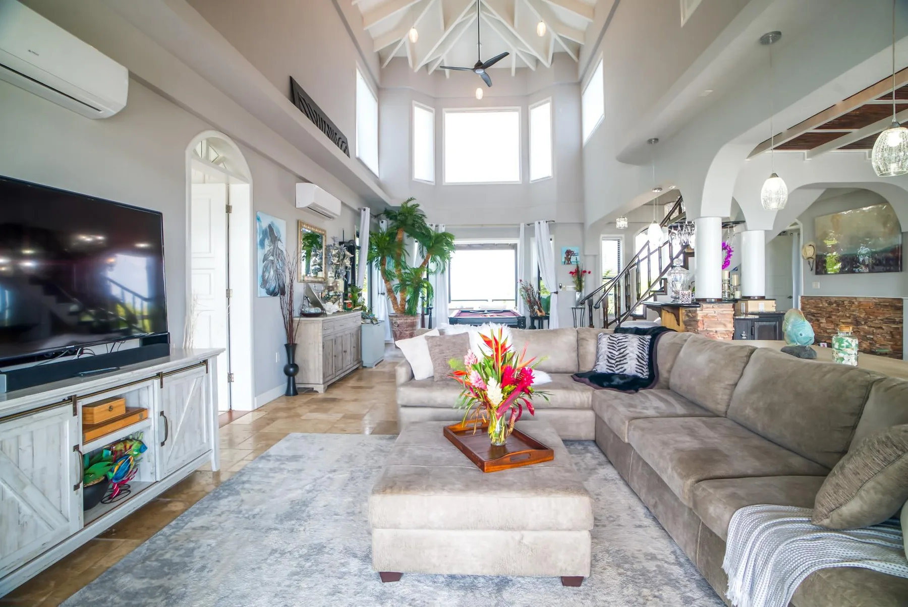 A bright living room with a large sectional seating area and high windows.