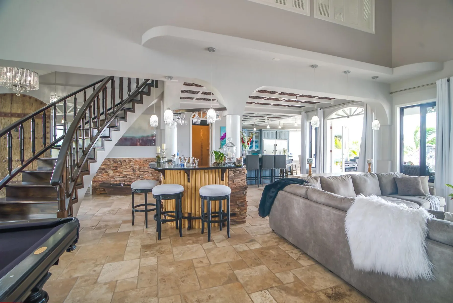 An open-plan living room and kitchen with a curved staircase and seating.