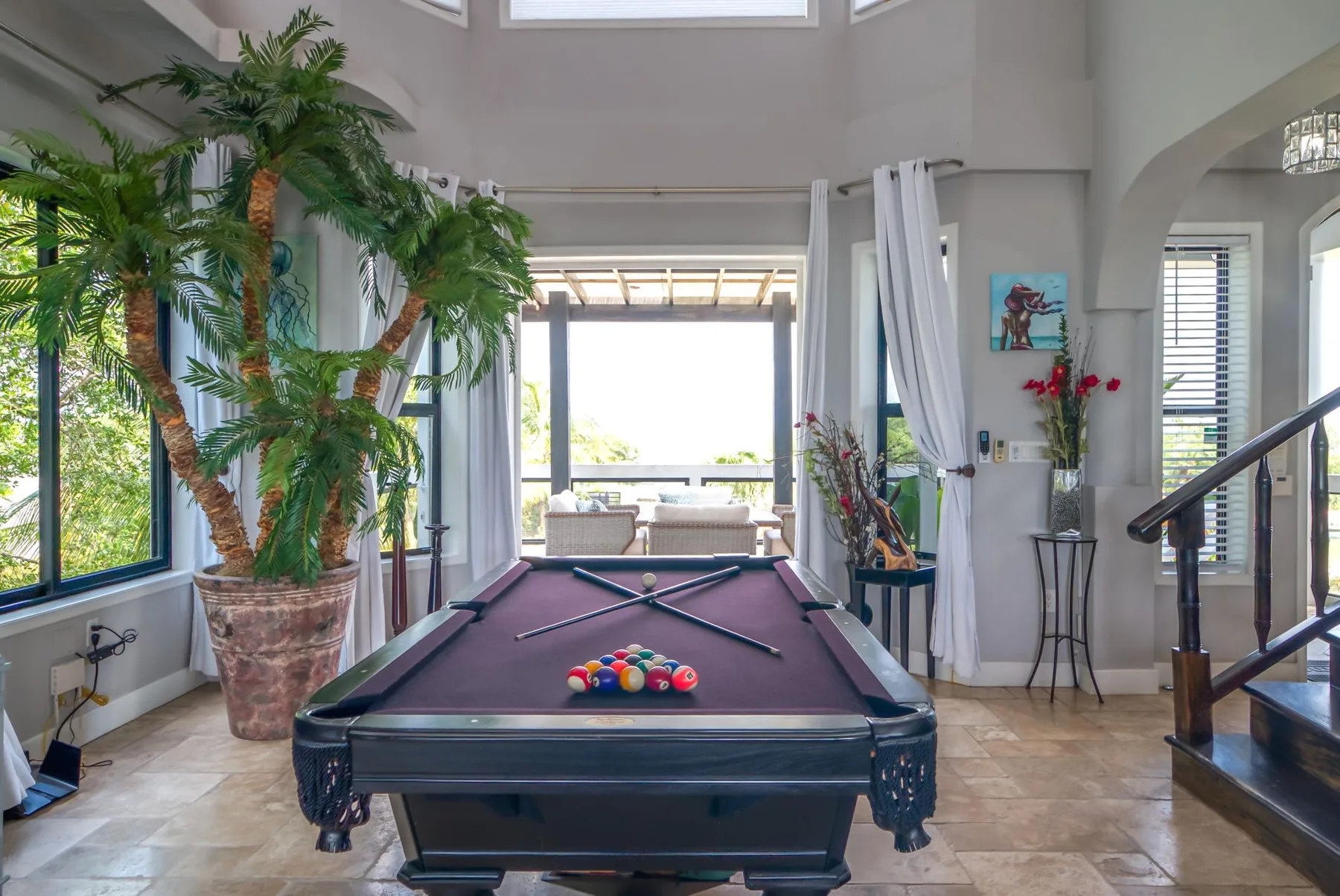 A recreation room features a pool table beside large windows.