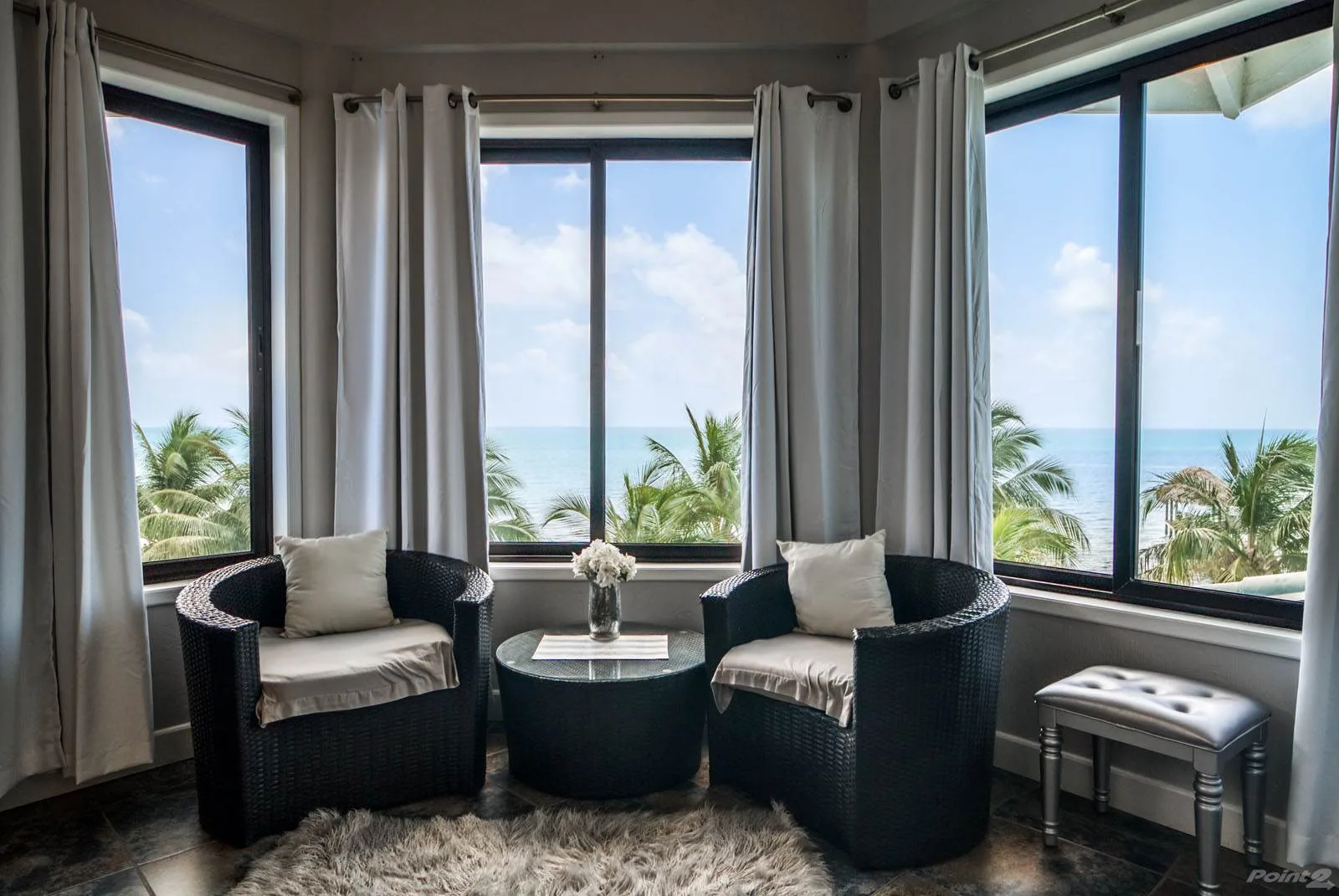 A sitting area with dark seating and large windows overlooking the ocean.