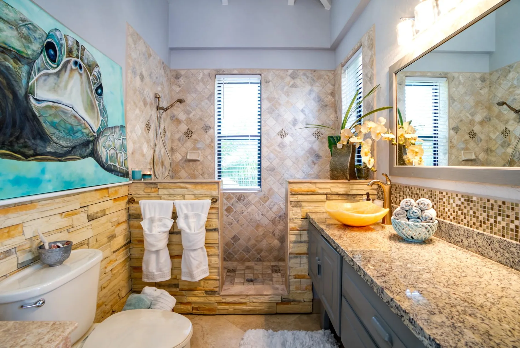 A tiled bathroom with a long vanity, sink, and large wall mirror.