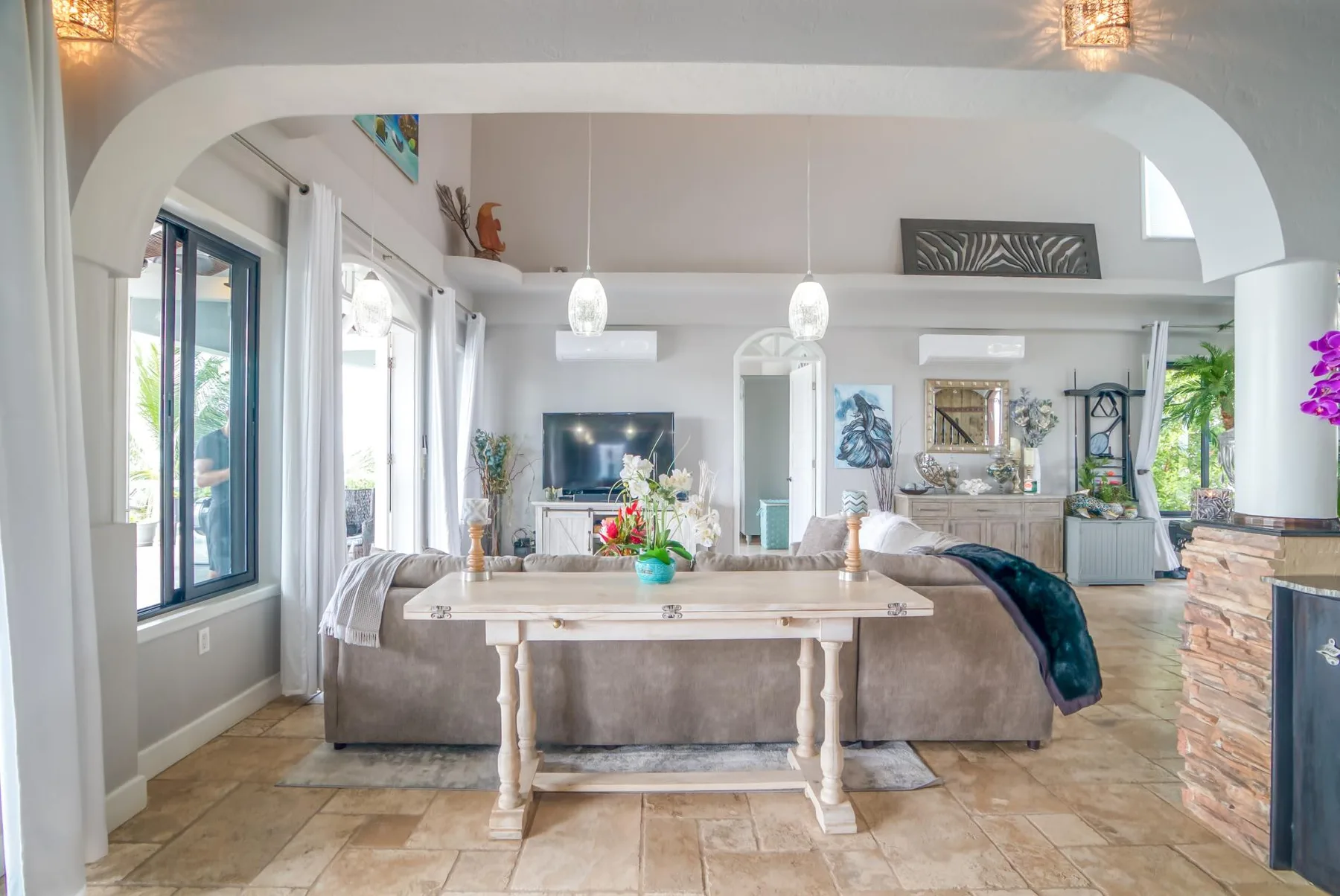 A bright living room with seating arranged around a coffee table beneath a wide arch.