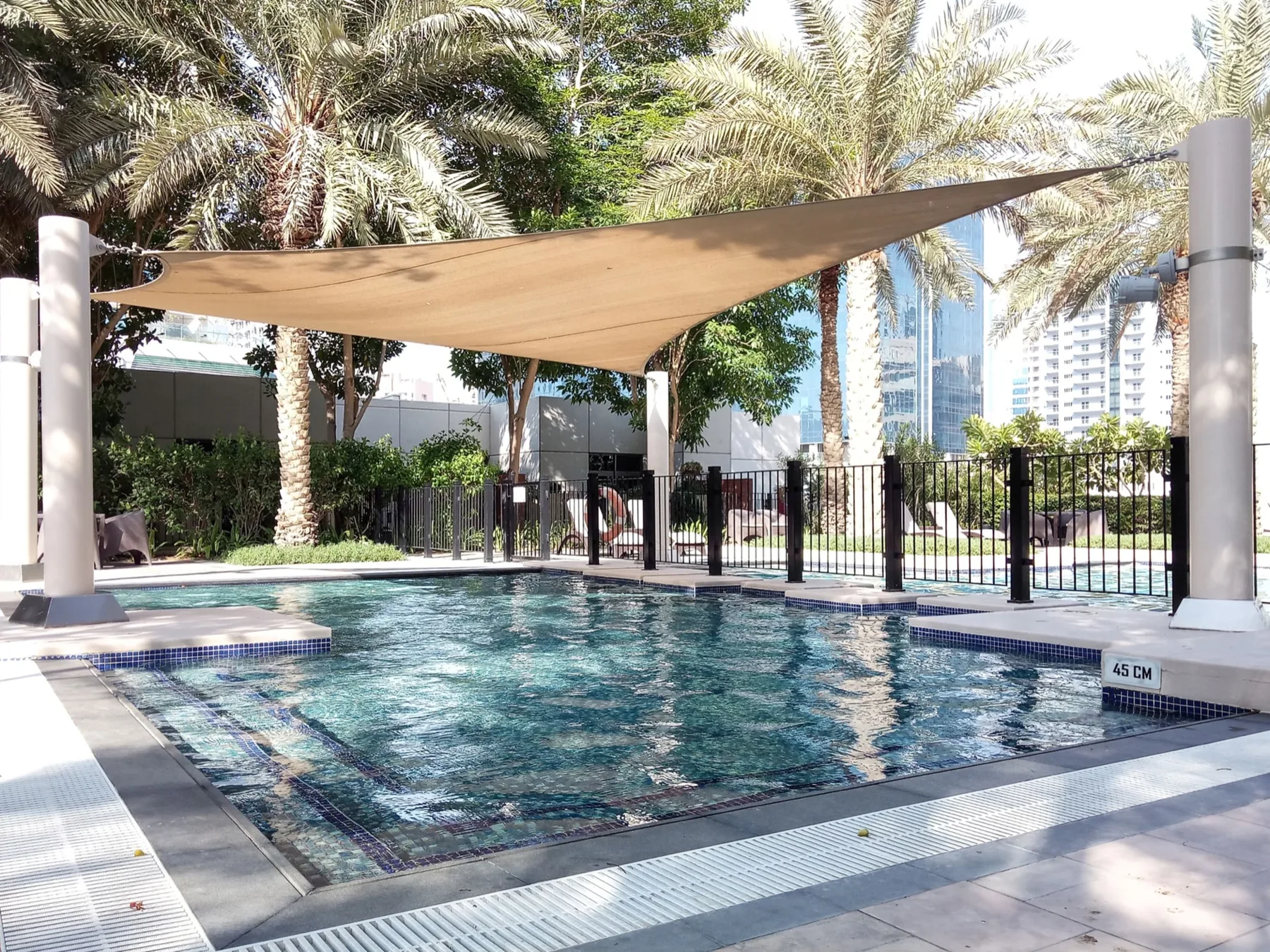 Shared amenity: A swimming pool sits beneath a shade canopy among palm trees.