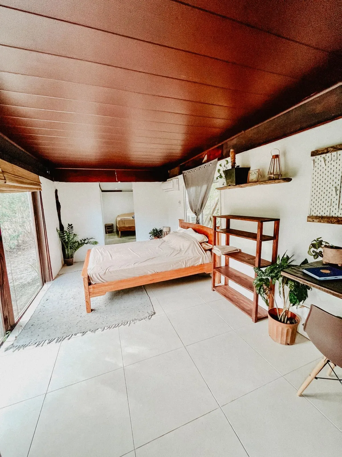 Representative hotel space: A bedroom with a bed, open shelving, and plants.