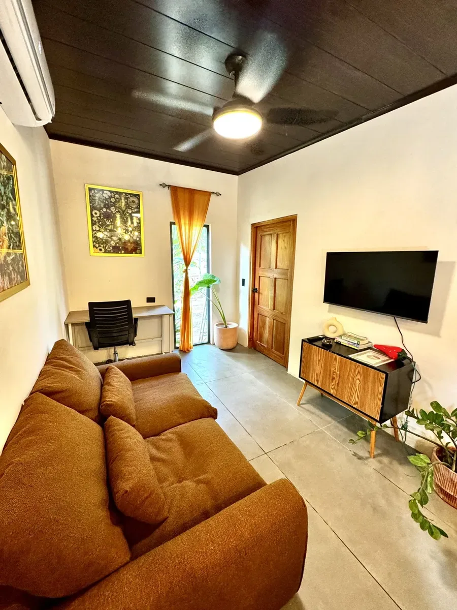 Representative hotel space: A living room with brown seating, a television, and a desk.