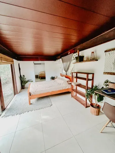 Representative hotel space: A bedroom with a low wooden bed, shelving, and a broad tiled floor.