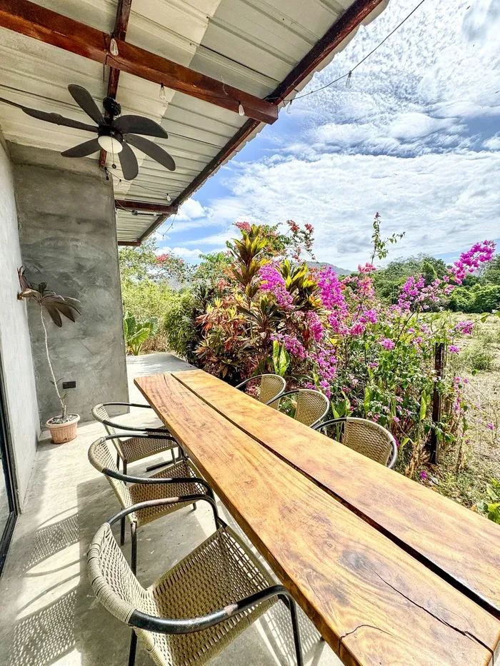 Representative hotel space: An outdoor dining area with a long wooden table overlooking flowering plants.