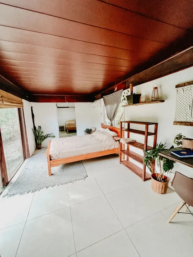 Representative hotel space: A bedroom with a wooden bed, shelving, and a large glass door.