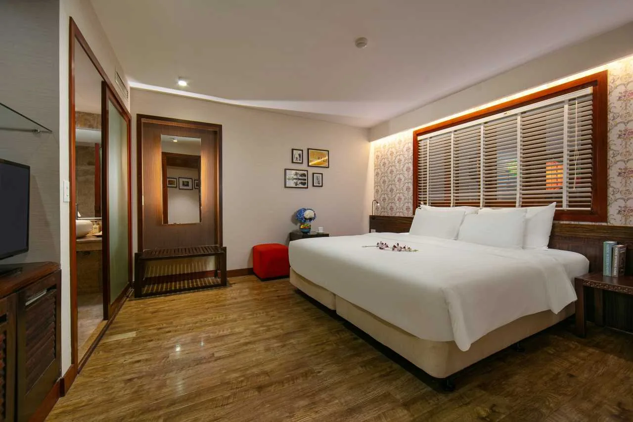 Espacio representativo del hotel: Un dormitorio de hotel con una cama grande bajo una ventana con persianas.