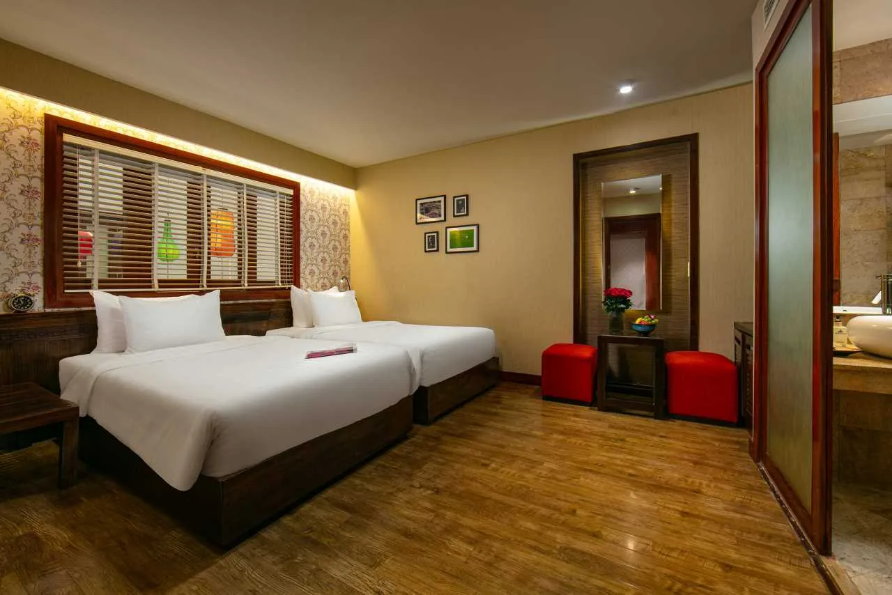 Espacio representativo del hotel: Un dormitorio con camas, suelo de madera y un armario con espejo.