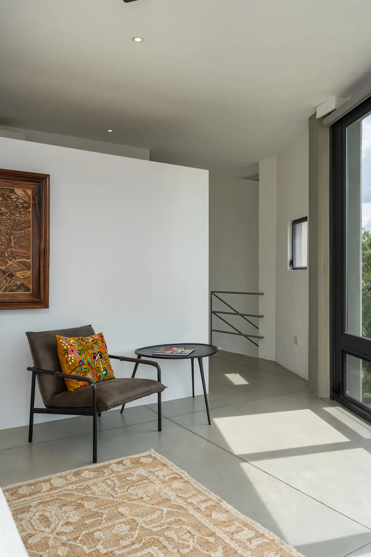 A bright modern sitting area with a lounge chair beside floor-to-ceiling windows.