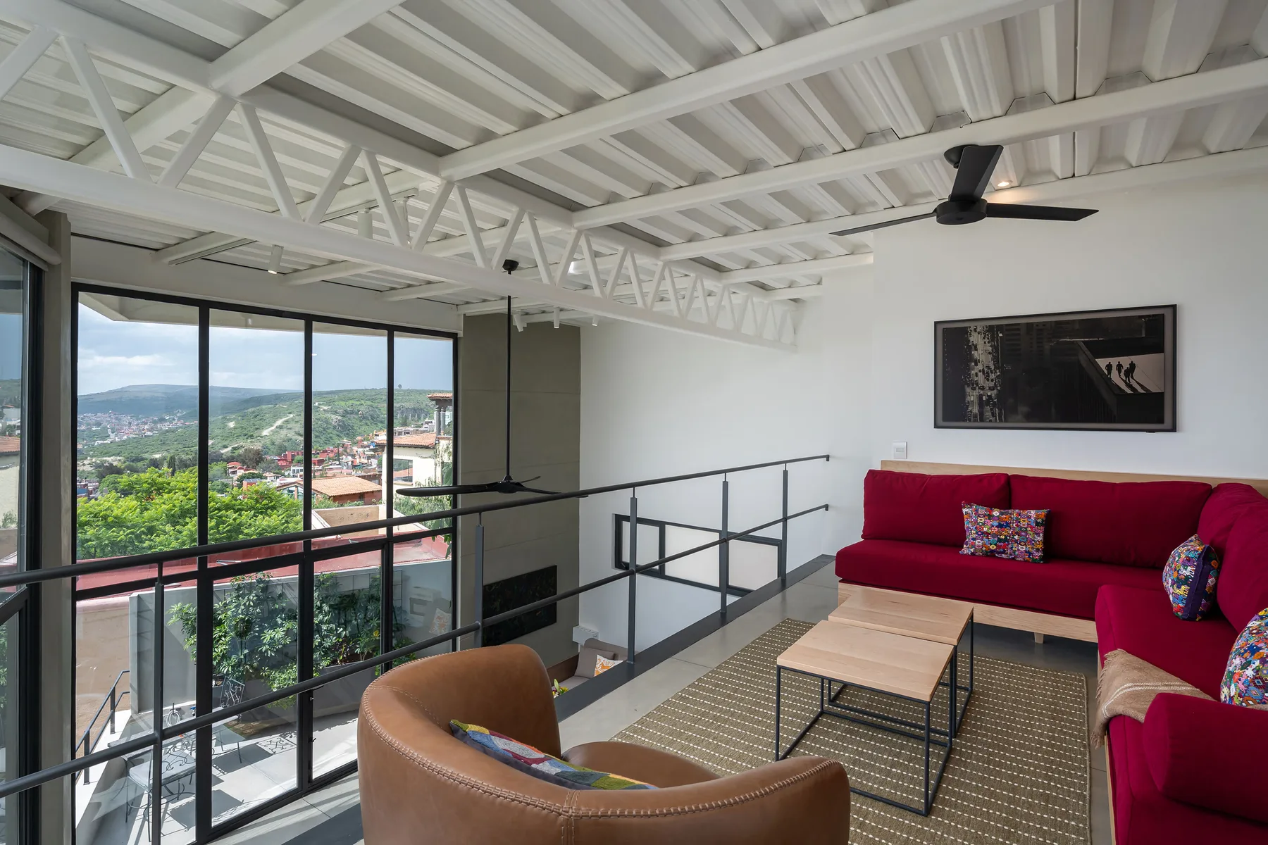 A living room with bright red seating, a coffee table, and large windows overlooking the city.
