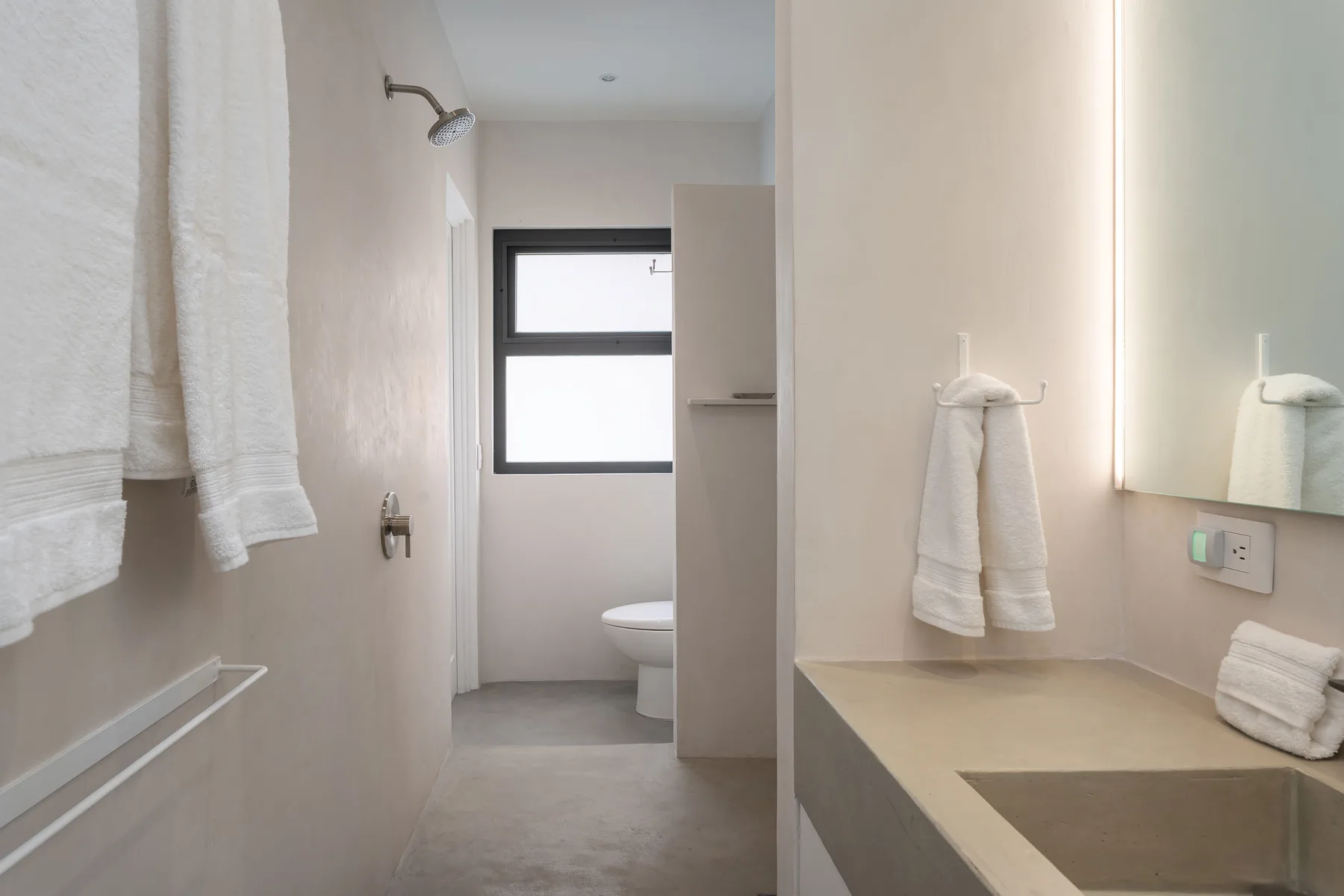 A bathroom with a shower, sink, and window.
