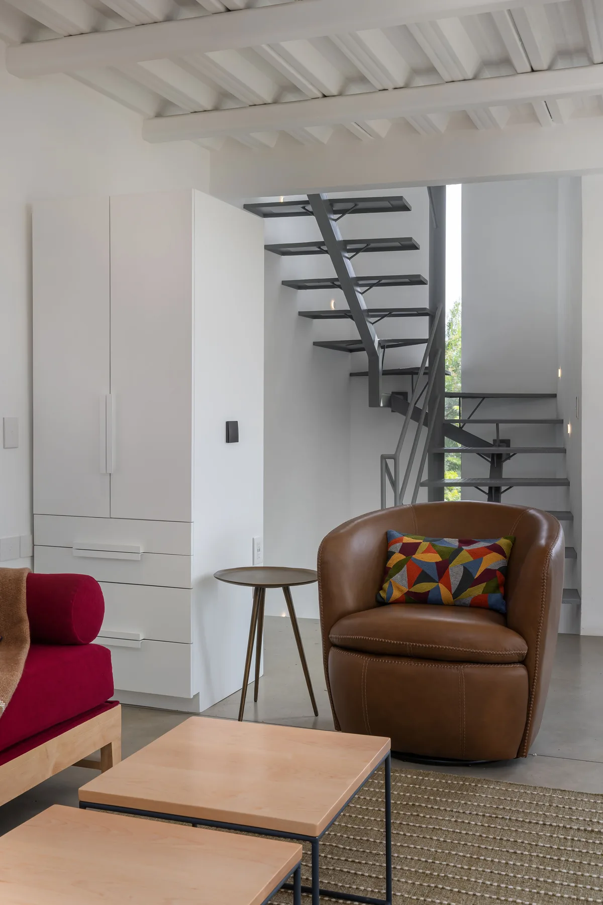A bright living area with a brown armchair and an open staircase.