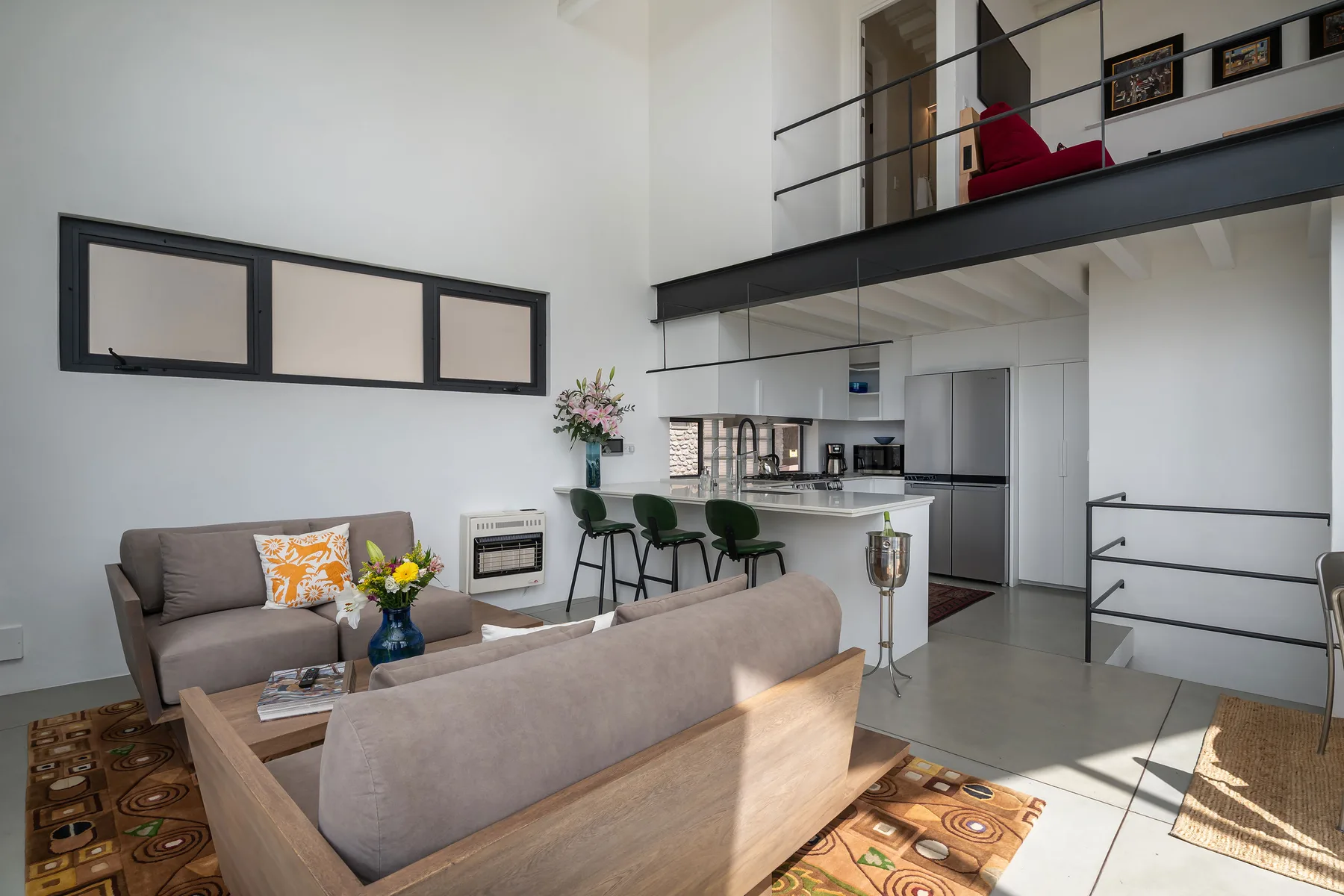 A bright open-plan living area with seating, a dining counter, and a kitchen.