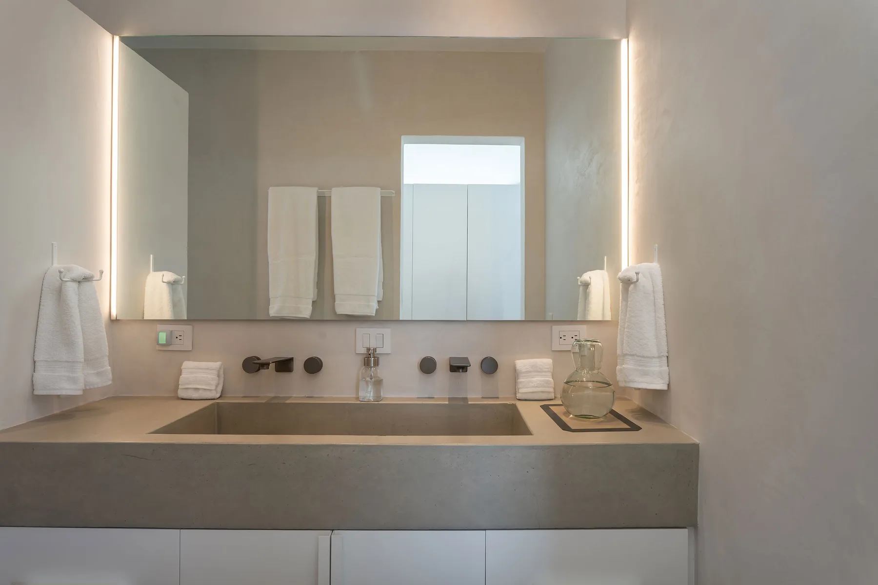 A bathroom vanity with a wide mirror, sink, and neatly hung towels.