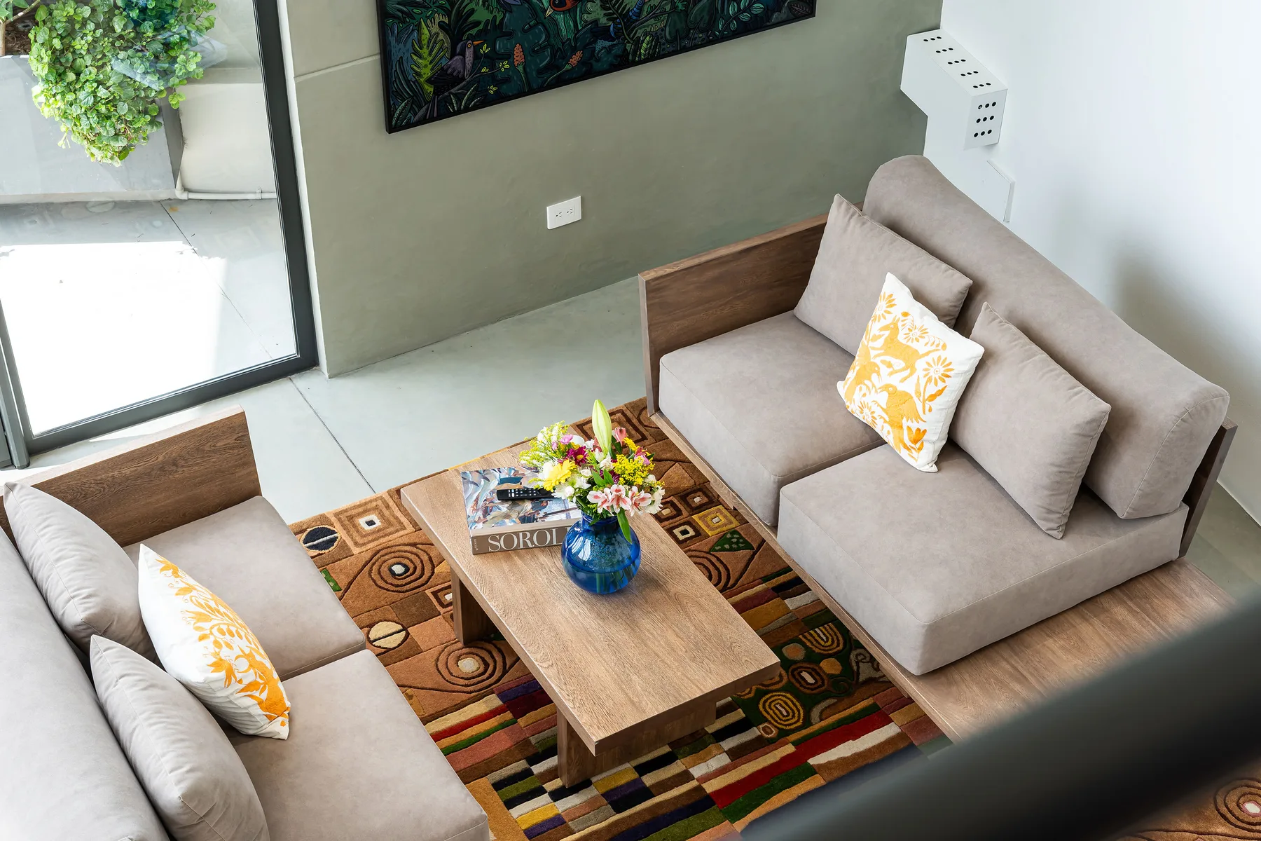 A living room with seating around a wooden coffee table and colorful rug.
