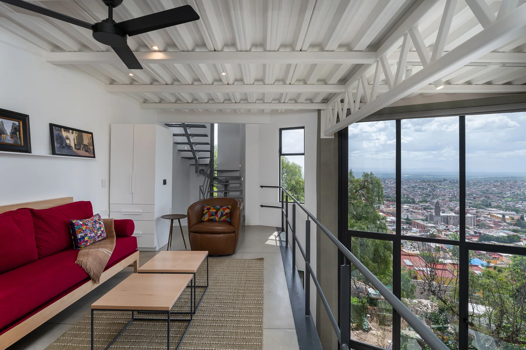 A bright living area with red seating and large windows overlooking the city.