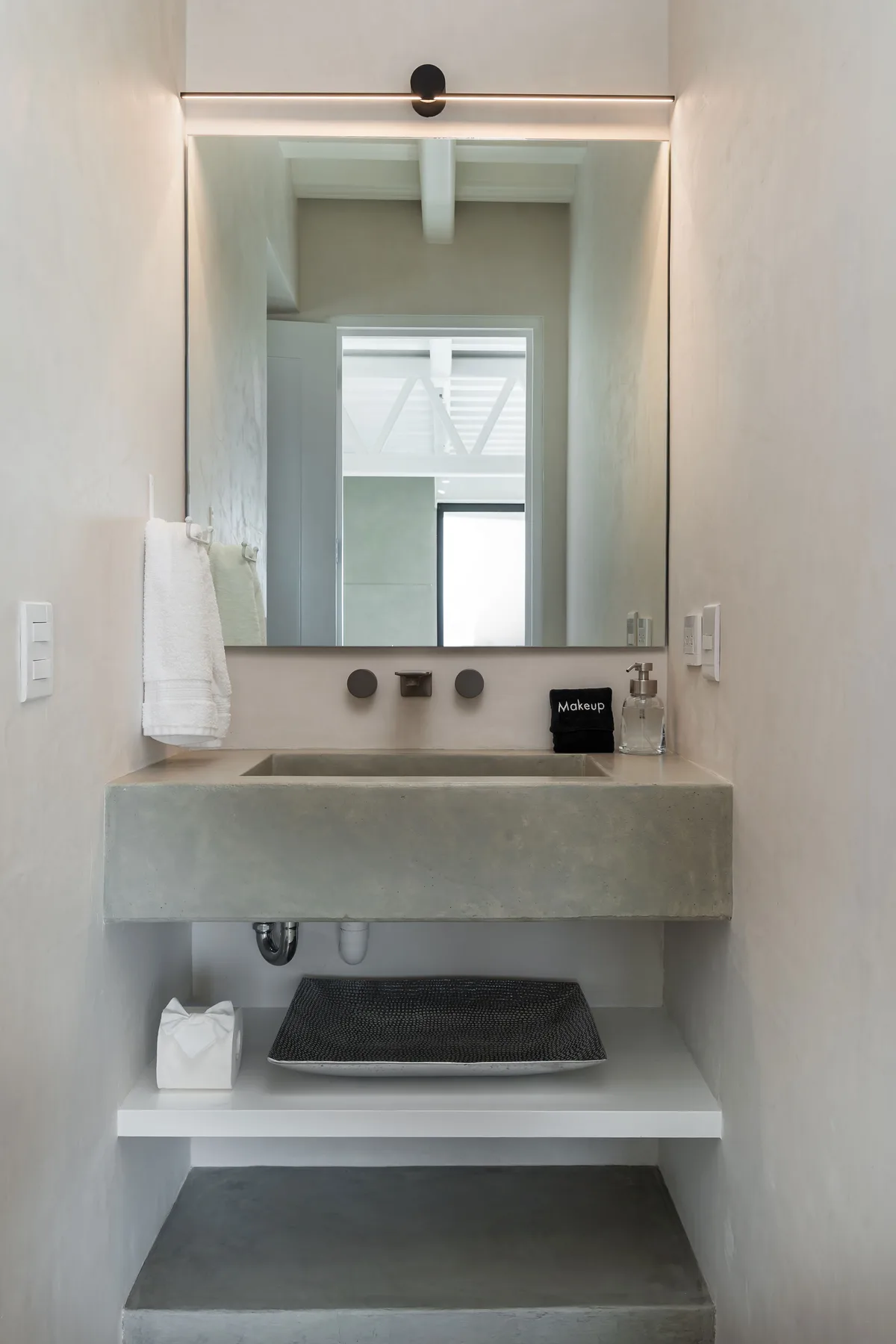 A narrow bathroom vanity with a large mirror and a vessel sink.
