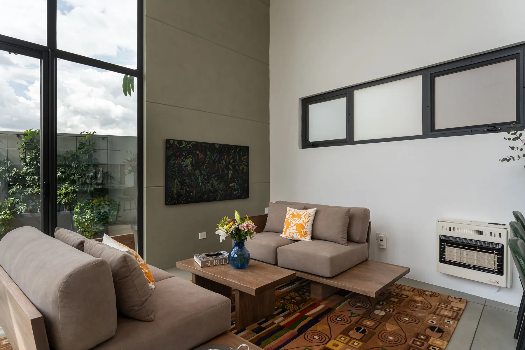 A bright living room with seating, a coffee table, and large windows.