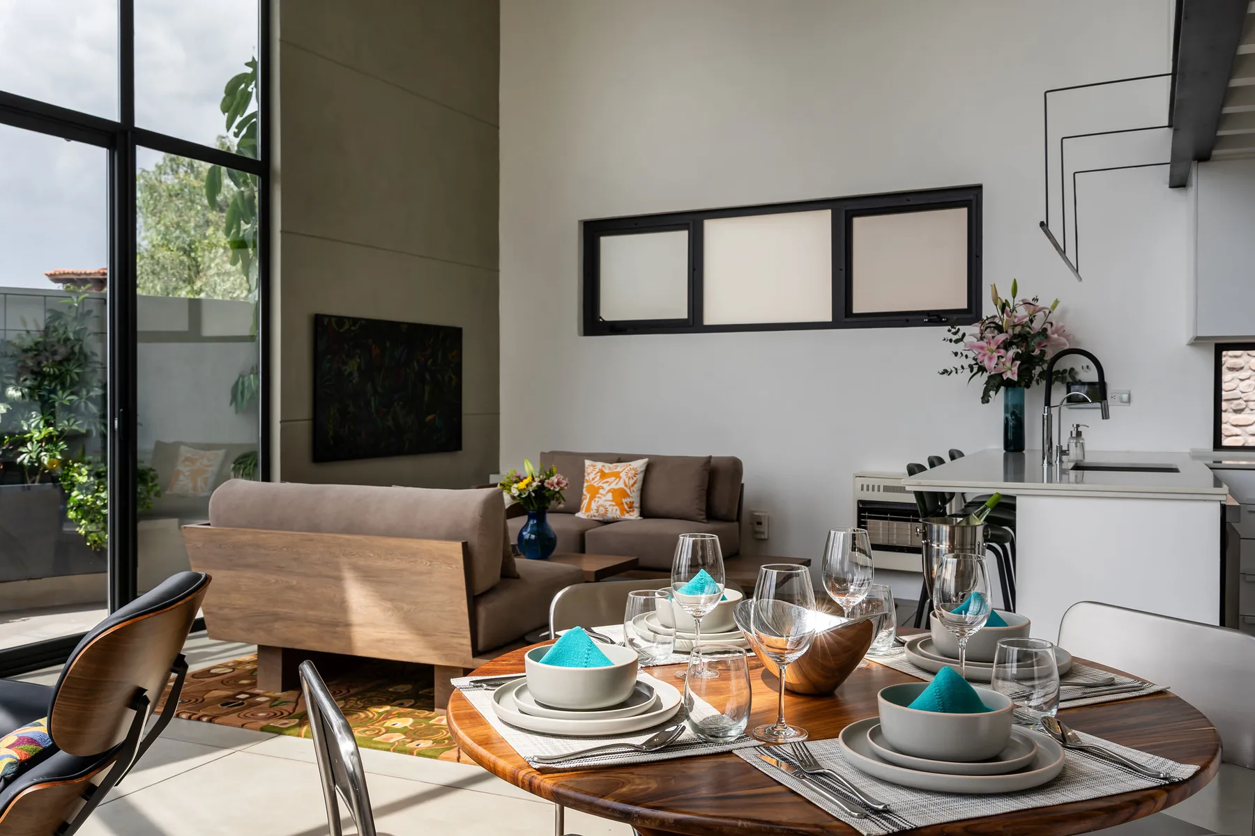 A dining area with a set table beside a living area and kitchen.
