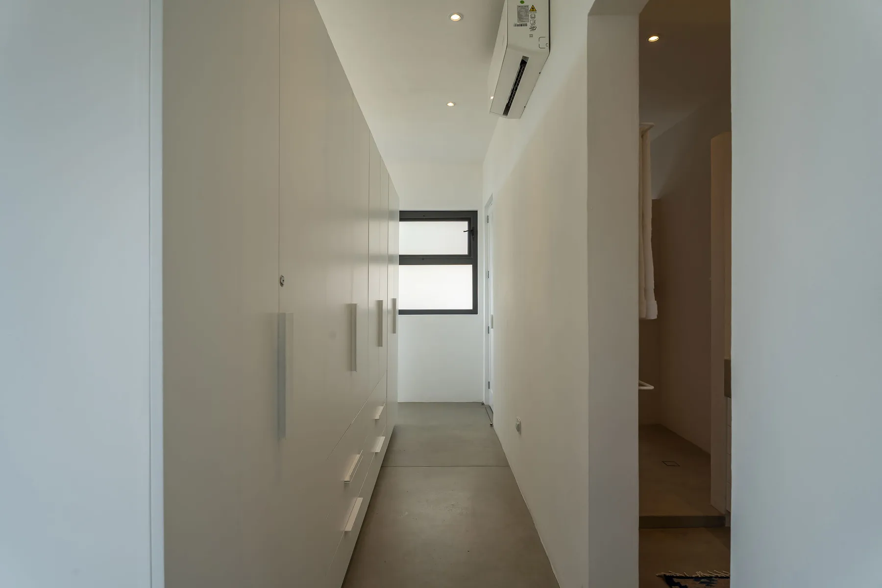 A narrow hallway with built-in cabinets and a window at the far end.