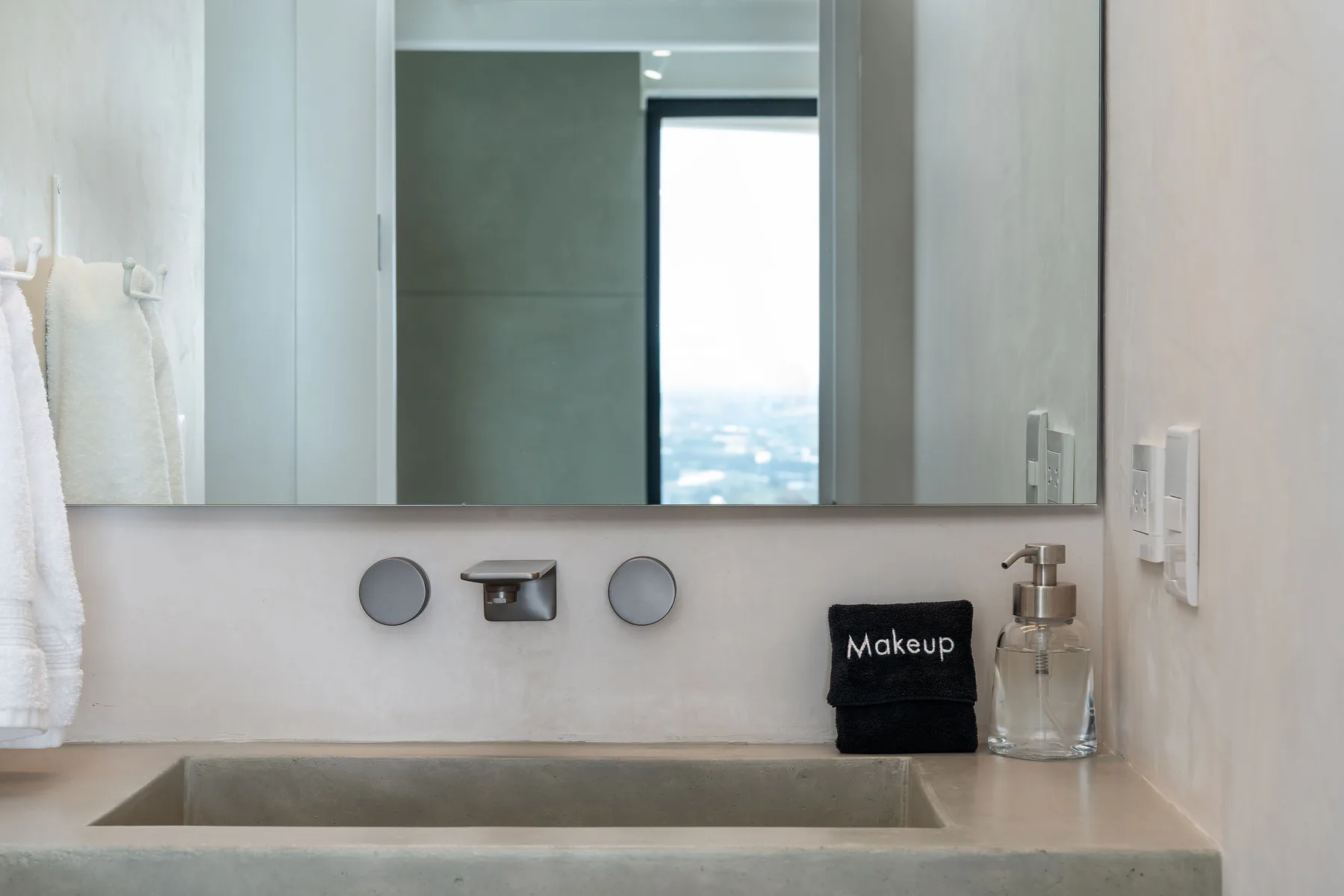 A bathroom vanity with a wide mirror, basin, and folded towels.
