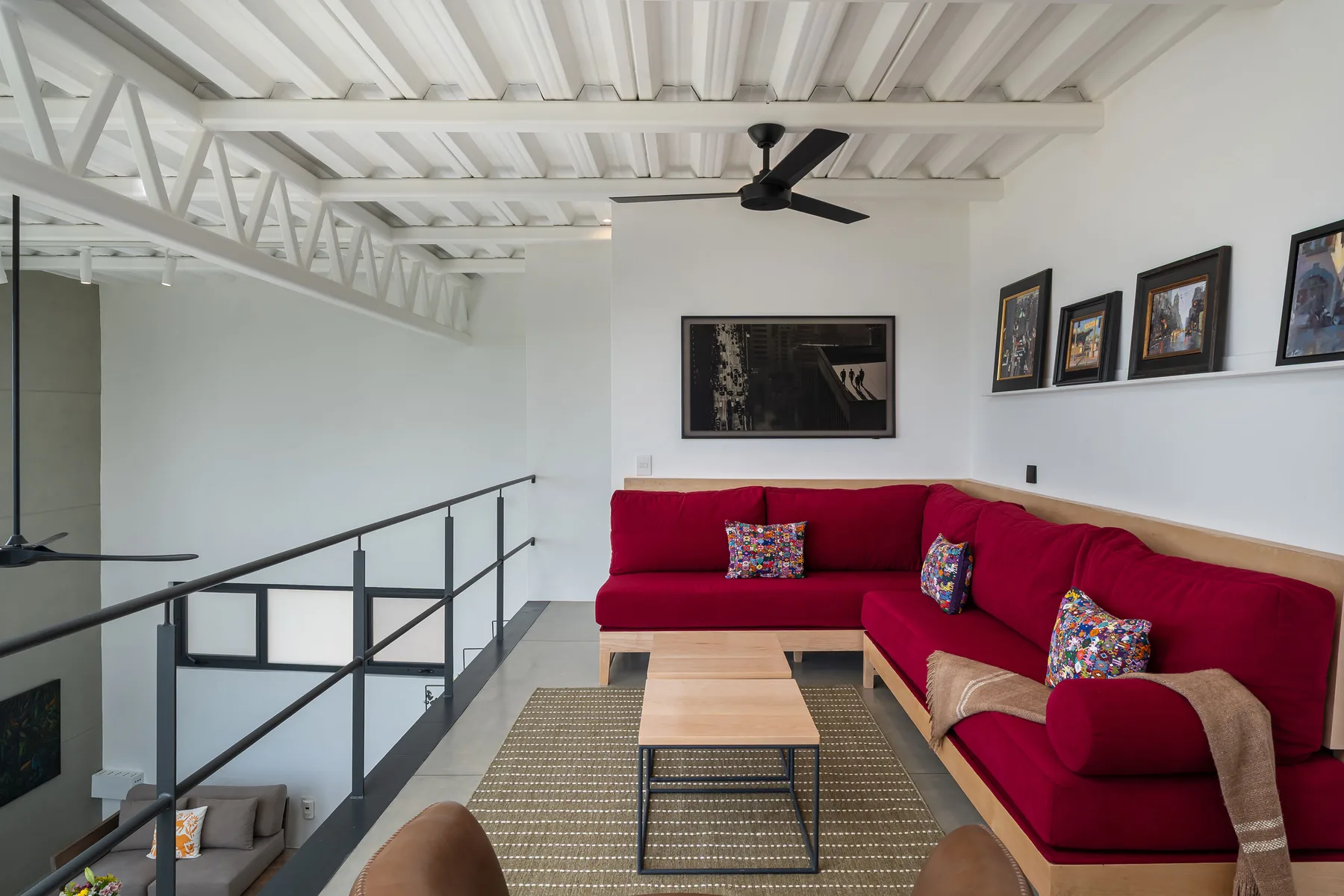 A bright living area with red sectional seating, a coffee table, and a ceiling fan.