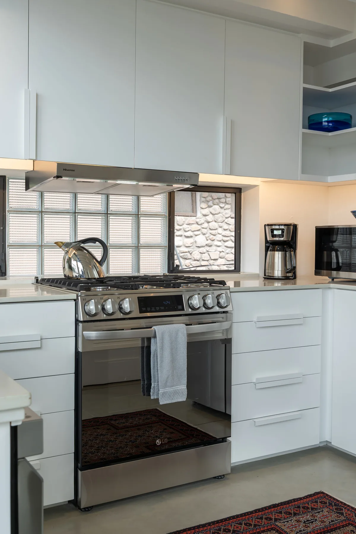 A modern kitchen with white cabinets and a stainless-steel range.