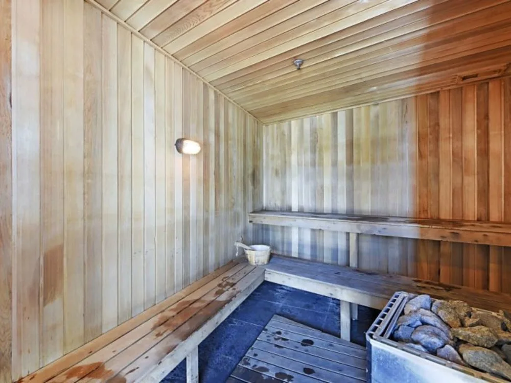 Shared amenity: A wooden sauna room with benches and a stone-filled heater.