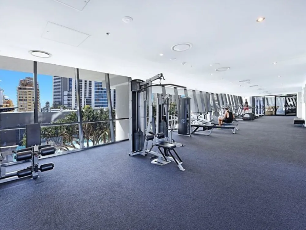 Shared amenity: A gym with exercise equipment arranged beside large windows.