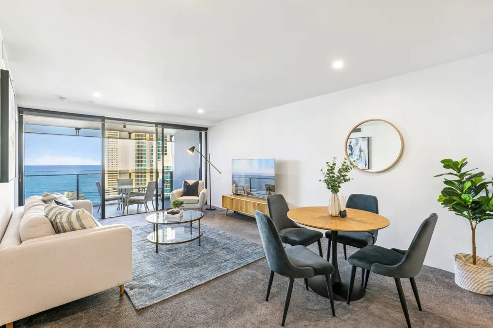 A bright open-plan living and dining area with seating beside large windows.