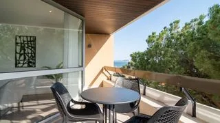 Una zona de comedor en el balcón tiene una mesa redonda y asientos bajo un techo cubierto.