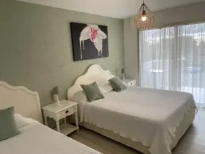 Espacio representativo del hotel: Un dormitorio con camas, mesillas y una gran ventana con cortinas.