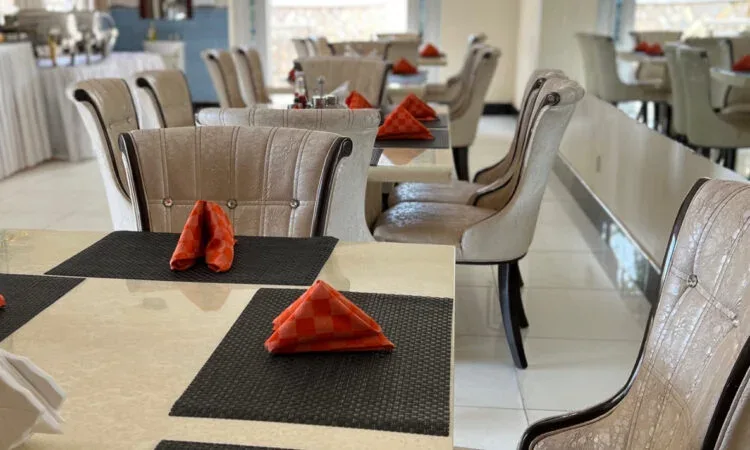 Representative hotel space: A dining area with tables set with folded red napkins.