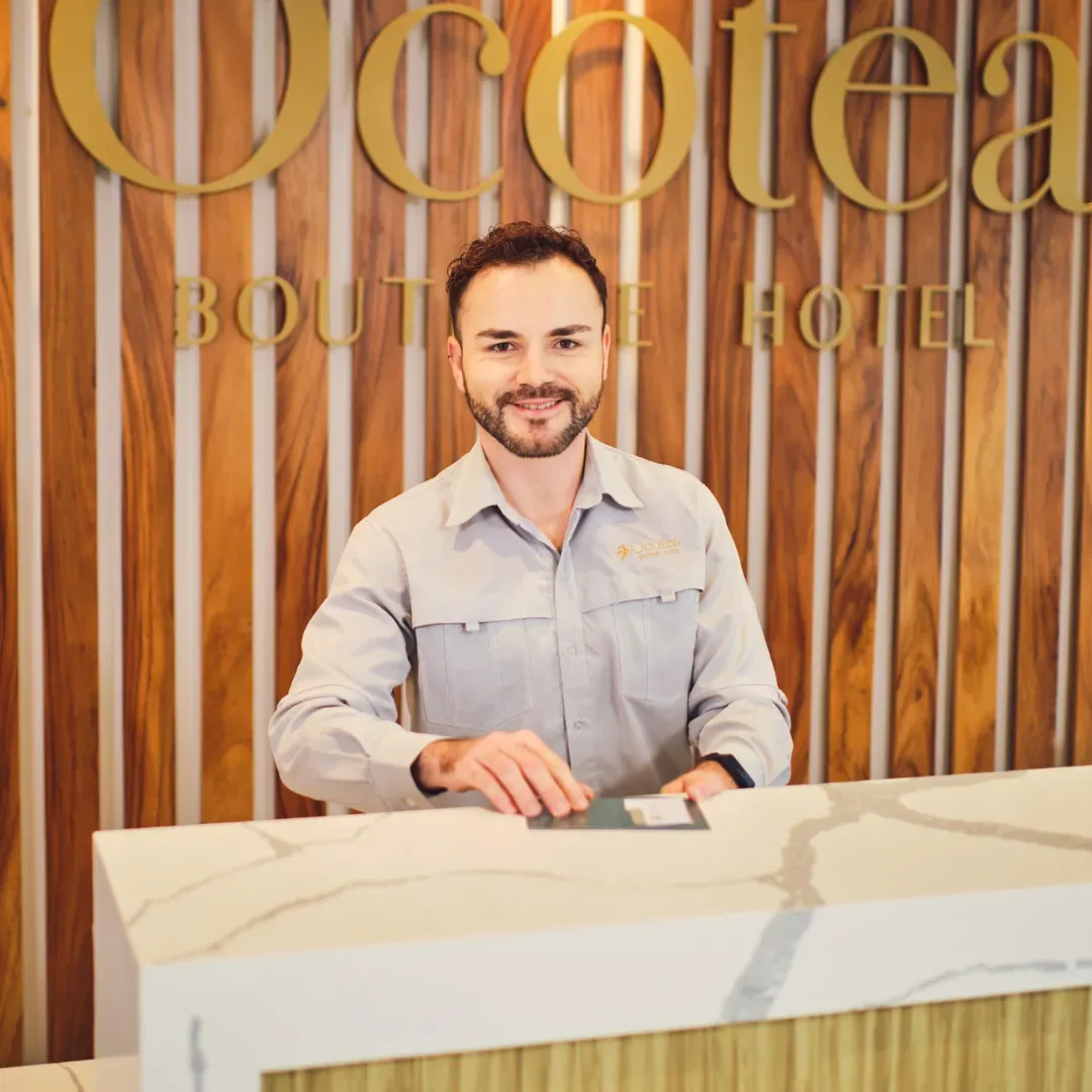 Espacio representativo del hotel: Un mostrador de recepción de hotel con un empleado detrás.