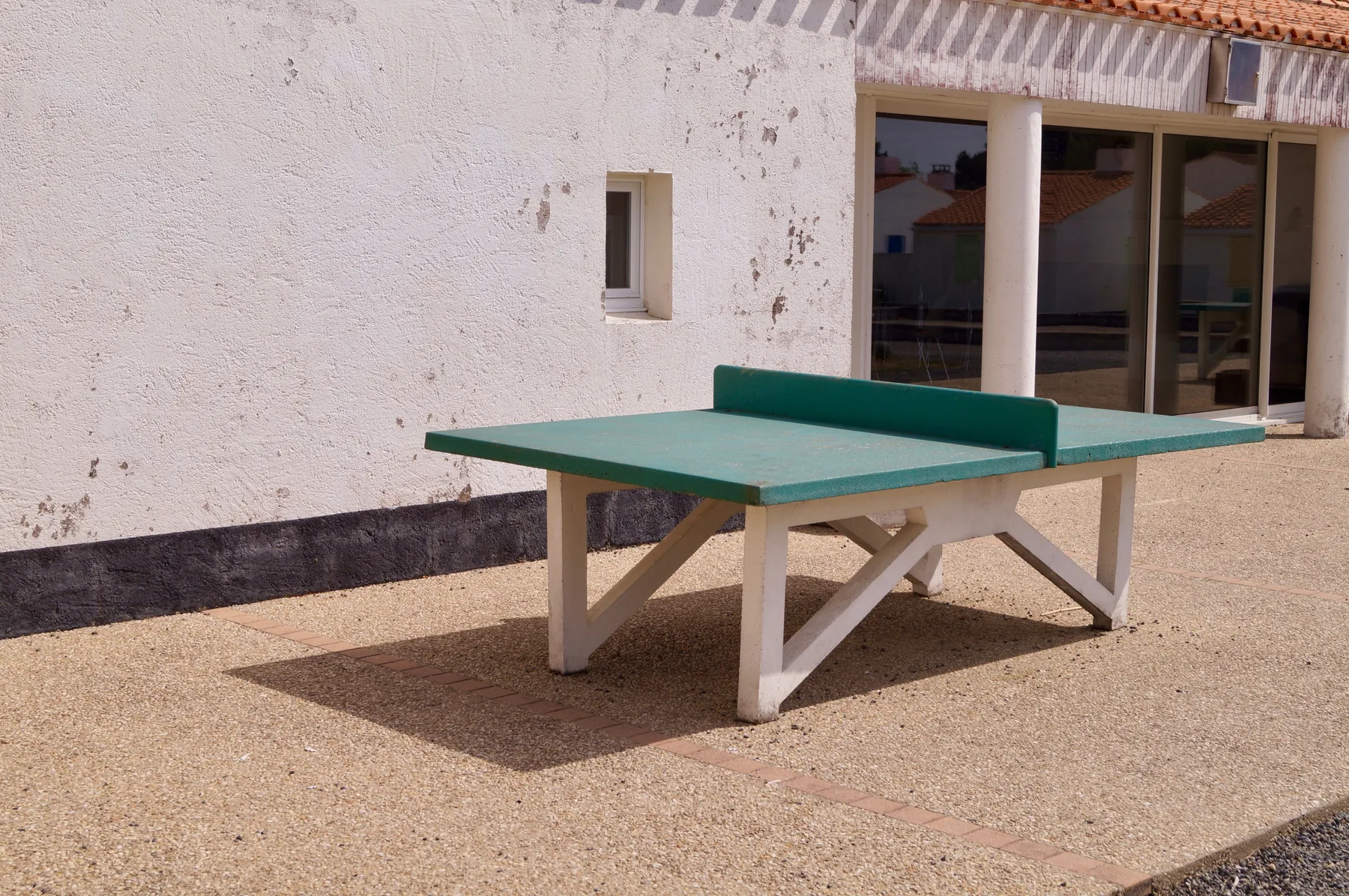 Shared amenity: An outdoor table tennis table stands on a paved patio beside a building.