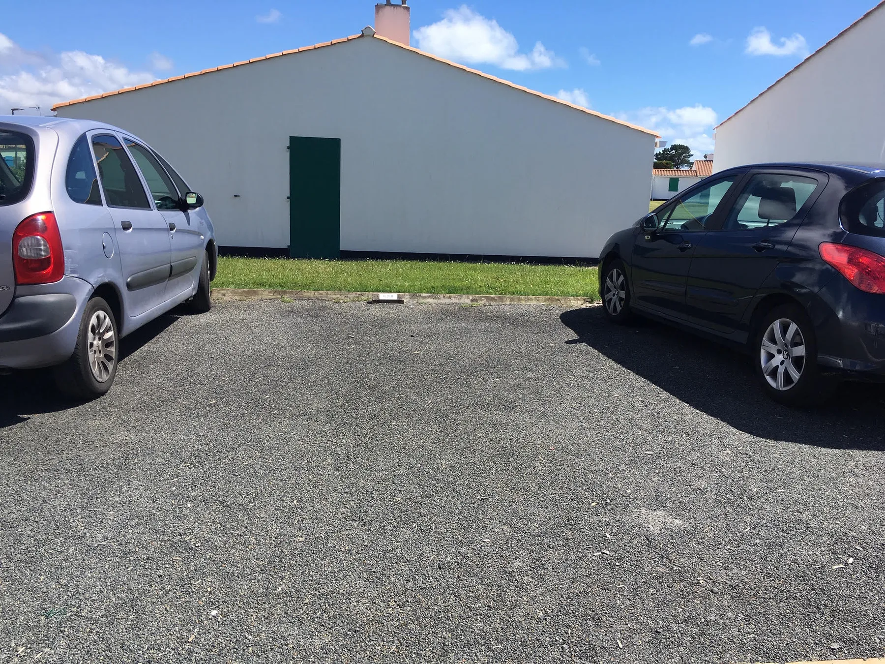 Shared amenity: An outdoor parking area with cars beside a plain building.
