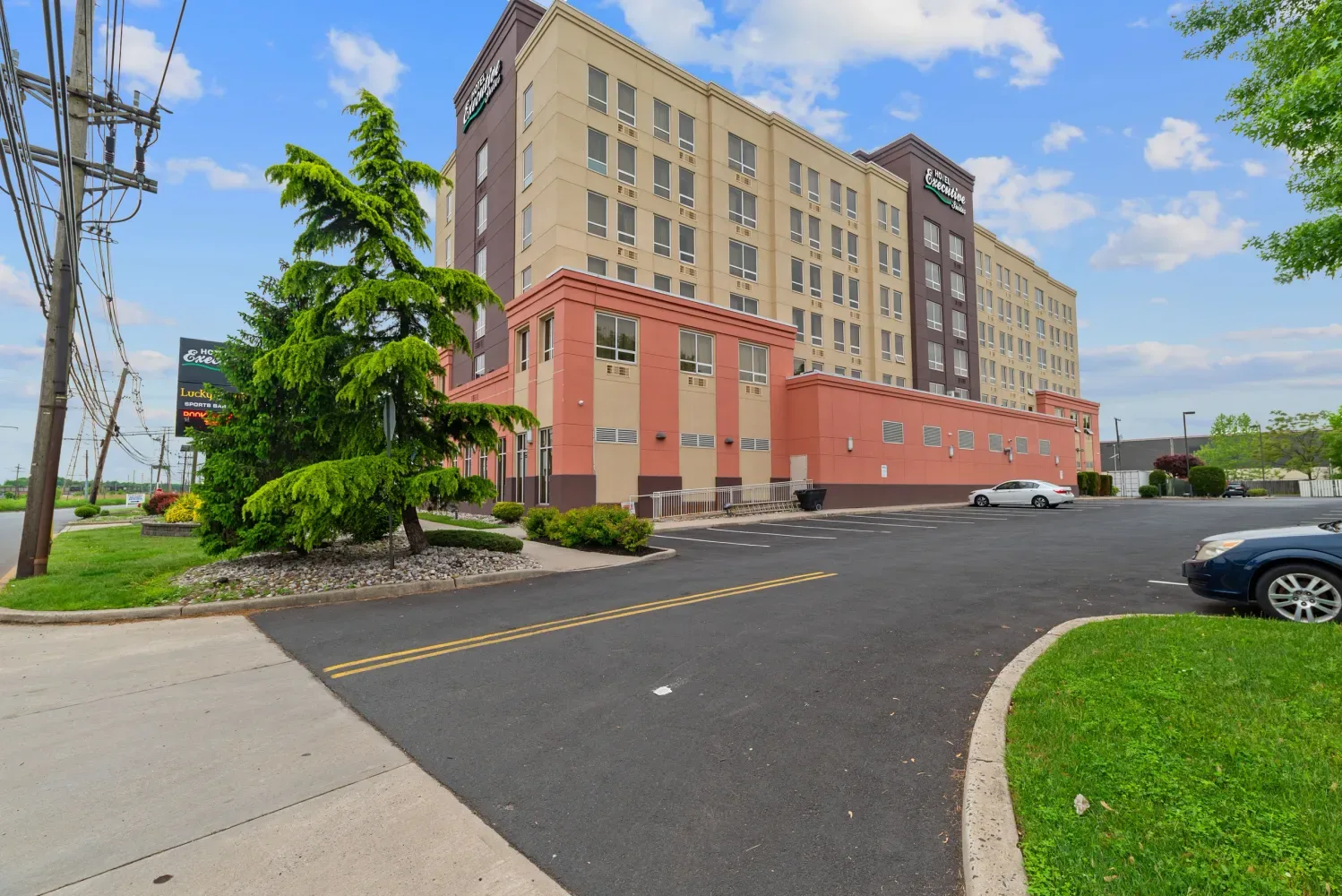 Representative hotel space: Hotel exterior beside a parking lot on a sunny day.