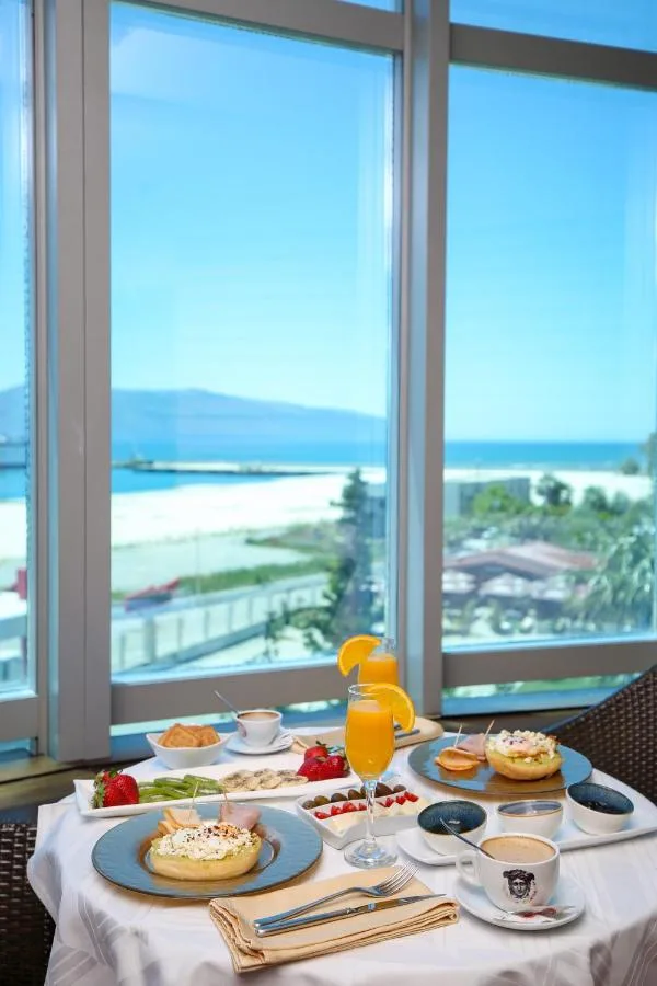 Representative hotel space: A breakfast table is set beside large windows overlooking the beach and sea.