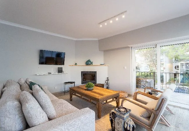 A living room with a coffee table, seating, and large windows opening to a balcony.