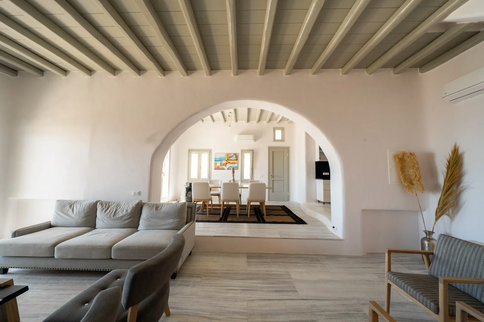 A bright living room with an arched opening to a dining area.