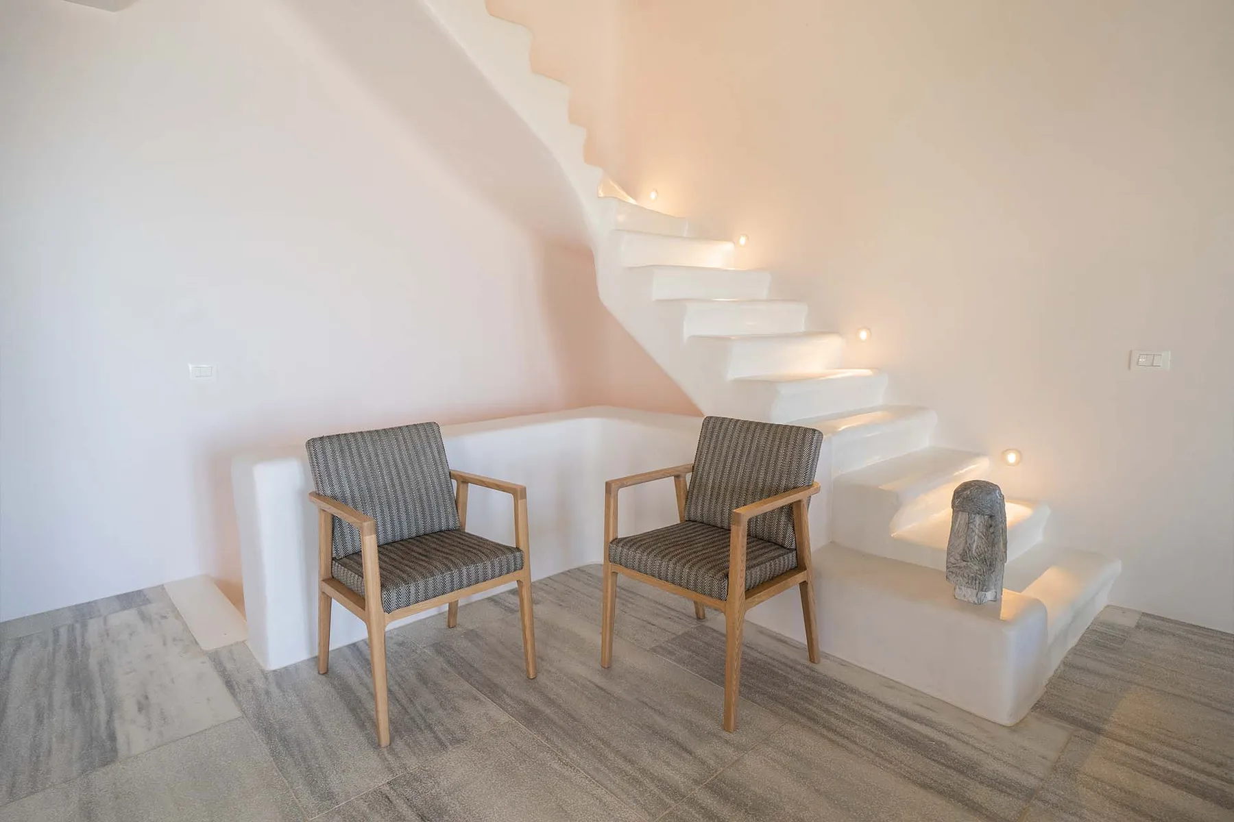 A bright interior seating area sits beside a curved staircase.
